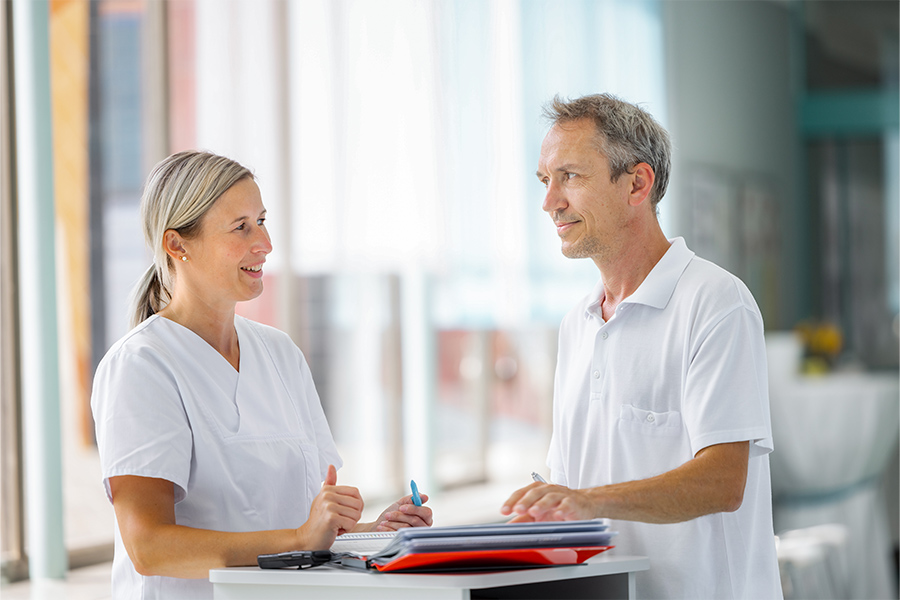 Ein Arzt und eine Pflegerin besprechen eine Patienten-Akte. Ein Arzt und eine Pflegerin besprechen eine Patienten-Akte.