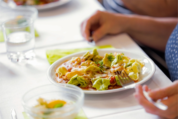 Auf einem Teller sind Tortellini mit Tomatensoße angerichtet.