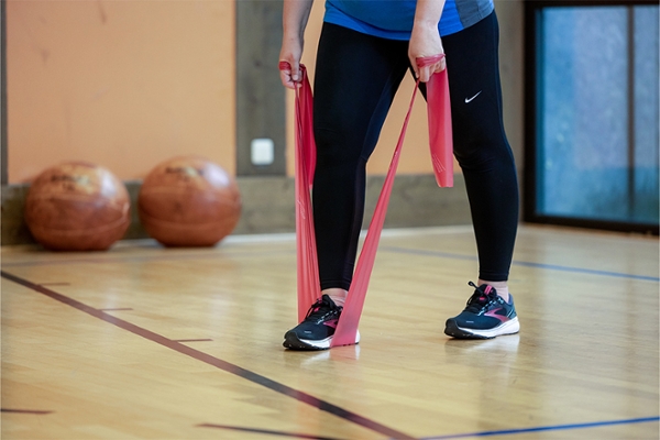 Eine Patientin trainiert in einer Sporthalle mit einem Fitnessband.