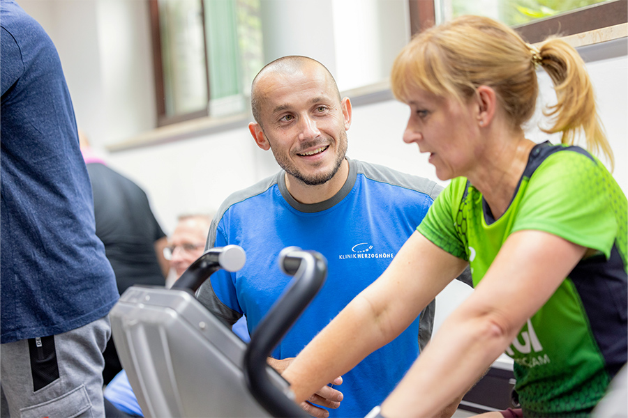 Ein Therapeut betreut eine Patientin beim Training auf dem Ergometer. Ein Therapeut betreut eine Patientin beim Training auf dem Ergometer.